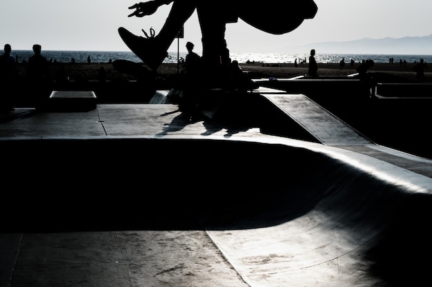 Eine selektive Fokusaufnahme einer Silhouette eines nicht erkennbaren Skateboarders, der verschiedene Tricks zeigt