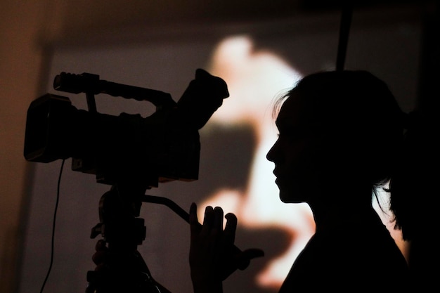 Eine Silhouette der jungen Frau des Videografen mit einer Videokamera