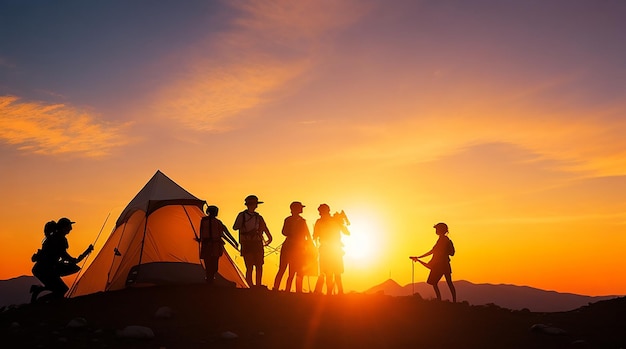 Eine Silhouette einer Gruppe von Menschen vergnügt sich während des Sonnenuntergangs auf dem Gipfel des Berges in der Nähe des Zeltes