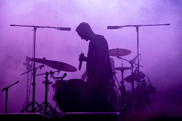 Foto eine silhouette eines hip-hop-rap-sängers während eines live-konzerts in dunklem licht. dunkler hintergrund, rauchscheinwerfer