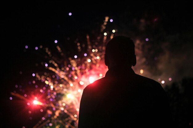 eine Silhouette eines Mannes vor Feuerwerk mit Feuerwerk im Hintergrund