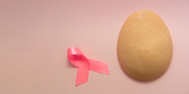 Eine Silikon-Brustprothese und Pink Ribbon Breast Cancer Concept mit Kopierraum