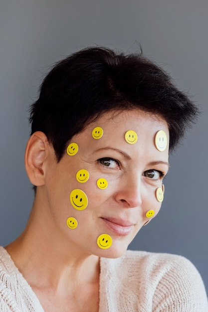 Foto eine spielerische junge brünette frau macht ein selfie mit emoticons auf ihrem gesicht