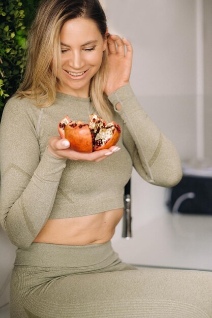 Eine sportliche Frau in Sportbekleidung hält eine Granate in der Hand Das Konzept der gesunden Ernährung