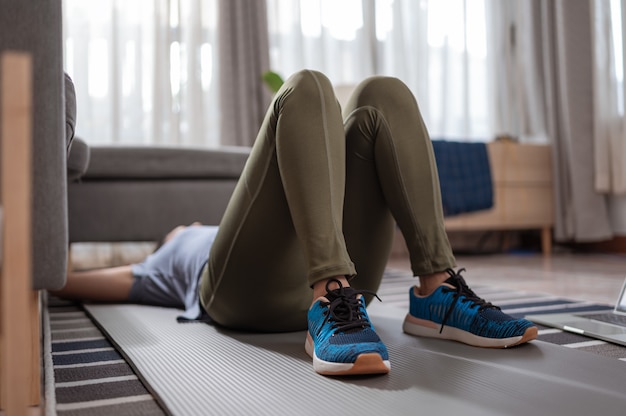 Eine sportliche Frau in Sportkleidung ruht sich zu Hause im Wohnzimmer auf dem Boden aus