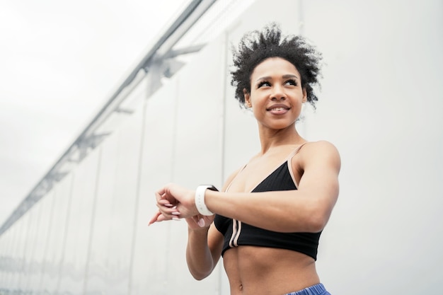 Eine sportliche Frau trainiert draußen mit einer Fitnessuhr