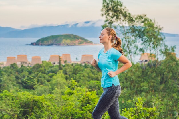 Eine sportliche junge Frau rennt gegen das Meer.