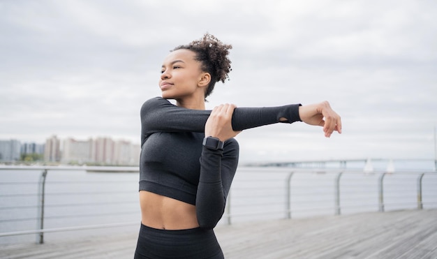 Eine sportliche Läuferin trainiert mit einer Fitnessuhr. Der Lauftrainer trägt einen Trainingsanzug