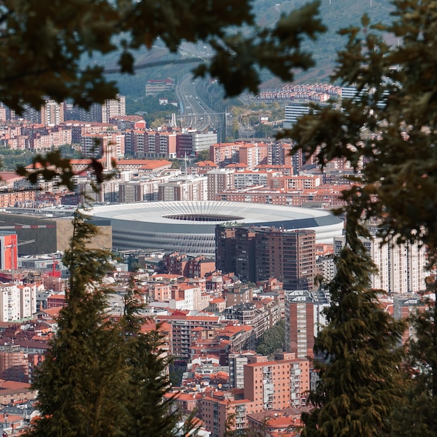 Eine Stadt mit einem weißen Stadion im Vordergrund und Bäumen im Hintergrund