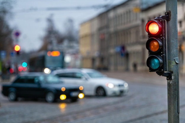 Eine Stadtüberquerung mit einem Semaphore auf verschwommenem Hintergrund mit Autos in den Abendstraßen rotes Licht