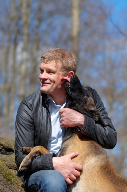 Eine starke Bindung Ein Mann und sein Hund sitzen zusammen im Wald