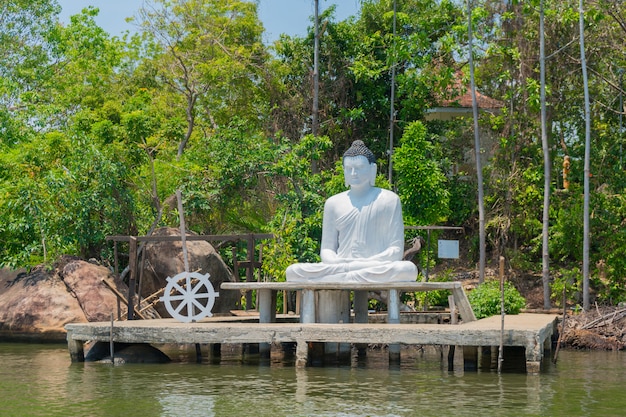 Eine Statue eines Sitzbuddhas an einem Fluss in Sri Lanka.