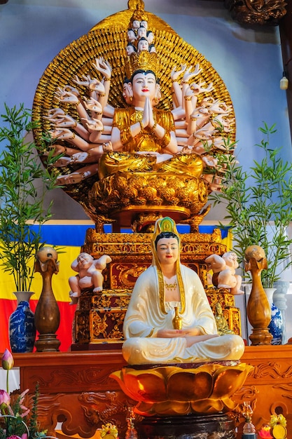 Eine Statue von Shiva und Buddha auf einem mit frischen Blumen geschmückten Altar in einem buddhistischen Tempel