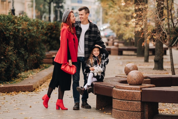 Eine stilvolle dreiköpfige Familie schlendert durch die Herbststadt und posiert für einen Fotografen Vater, Mutter und Tochter in der Herbststadt