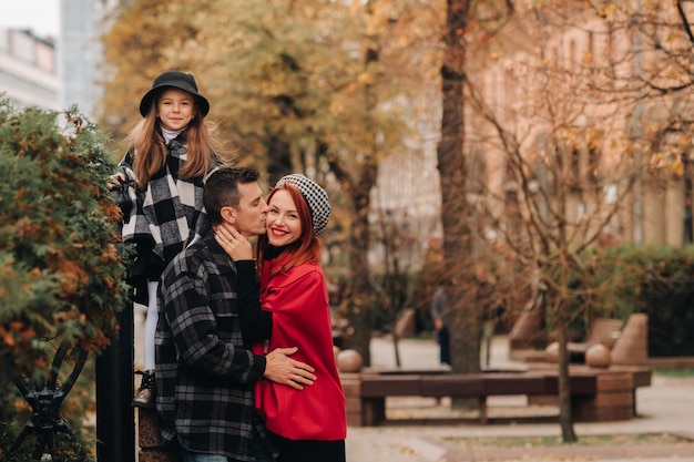 Eine stilvolle dreiköpfige Familie schlendert durch die Herbststadt und posiert für einen Fotografen Vater, Mutter und Tochter in der Herbststadt