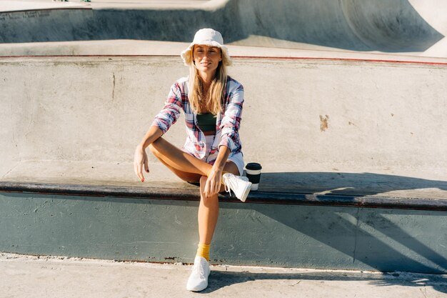 Foto eine stilvolle frau in einem panamahut sitzt an einem sommertag in einem skatepark