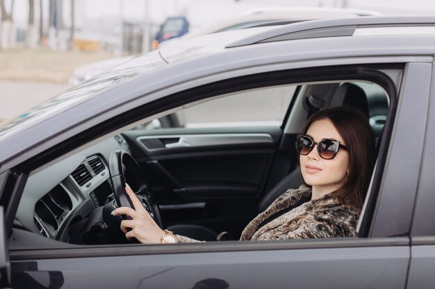 Eine stilvolle junge Frau sucht ein neues Auto in einem Autohaus