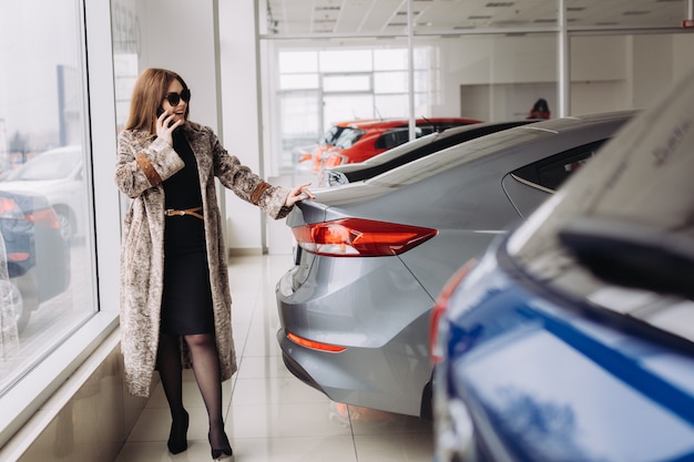 Eine stilvolle junge Frau wählt ein neues Auto in einem Autohaus