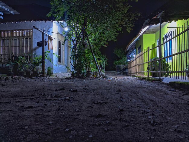 Eine Straße bei Nacht mit einem grünen Haus und einem Haus mit einem weißen Zaun.