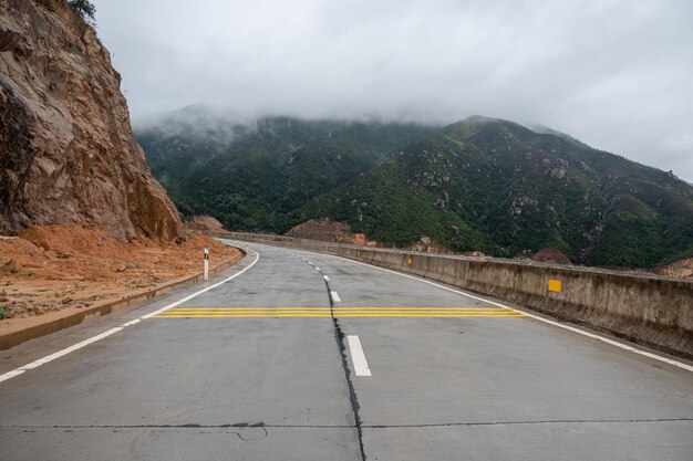 Eine Straße, die zu den Bergen führt. Nebel liegt auf den Bergen