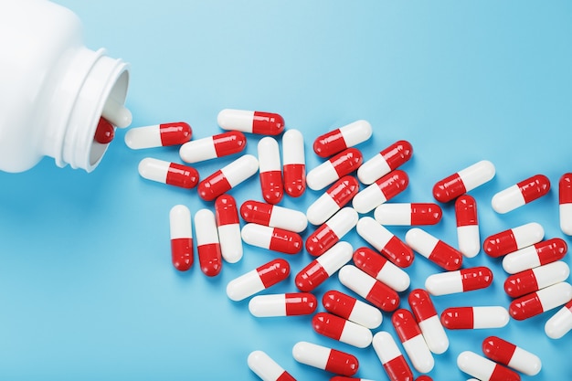 Eine Streuung weißer Dosen mit roten und weißen Ampullen mit Medikamenten und Vitaminen auf blauem Hintergrund