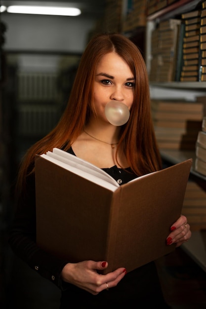 Eine Studentin in der Bibliothek hält ein Buch in der Hand und verbringt ihre Freizeit