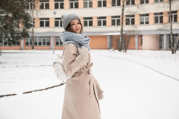 Eine Studentin mit weißem Rucksack geht im Winter unter den Schnee, um zu lernen