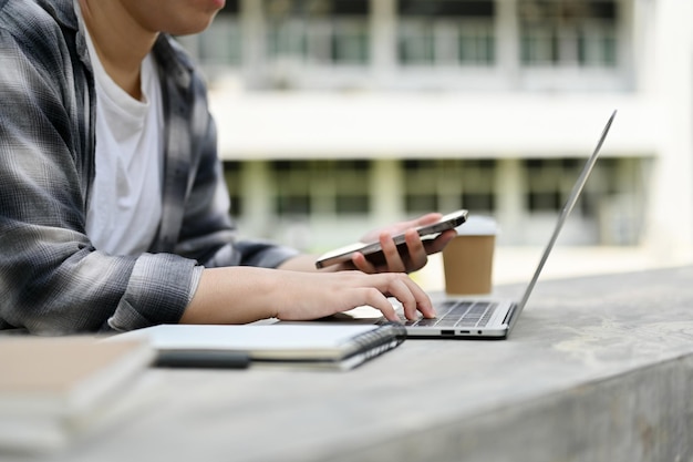 Eine Studentin sitzt im Campuspark und sucht auf ihrem Laptop nach Informationen