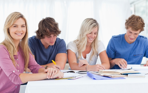 Eine Studiengruppe arbeitet hart als ein Mädchen lächelt und schaut in die Kamera