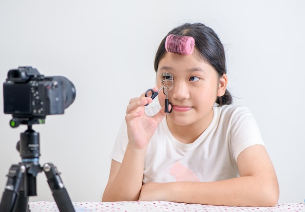 Eine süße asiatische Bloggerin zeigt, wie man sich schminkt und einen Wimperncurler benutzt