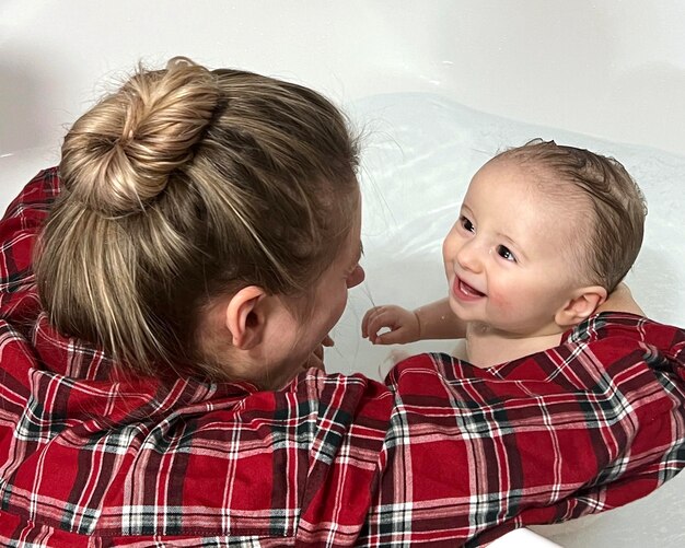 Foto eine süße mutter badet einen jungen in klarem wasser in einer badewanne