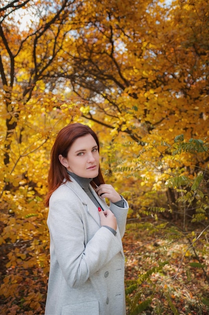 Eine süße rothaarige Frau in guter Laune posiert an einem Herbsttag