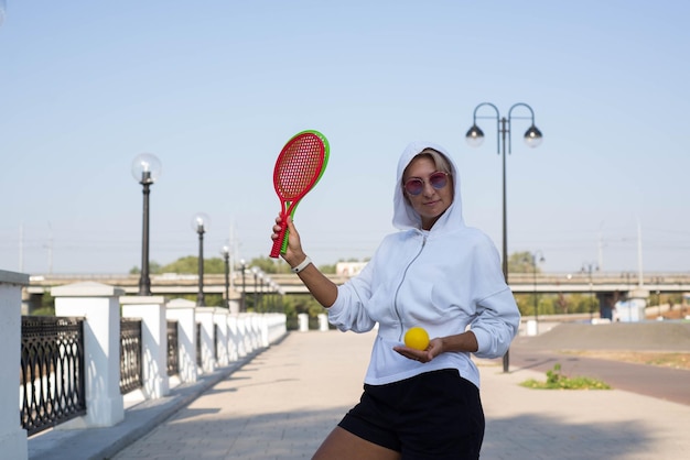 Eine süße sportliche Frau hält Schläger und Ball im Freien