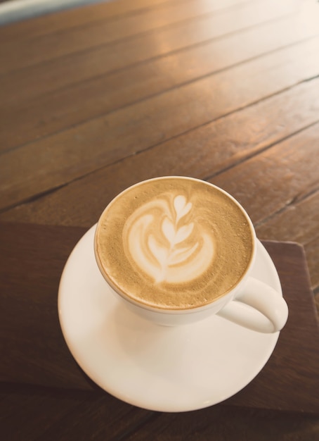 Eine Tasse Cappuccino-Kaffee auf Holztisch im Café Hintergrund mit Vintage-Filter