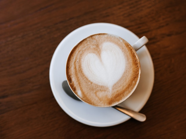 Eine Tasse Cappuccino mit Latte Art auf Holztisch, weiße Keramikschale, Draufsicht. Cafe Kultur.