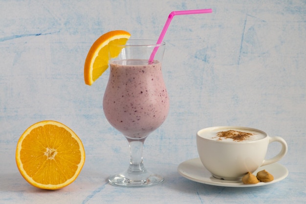 Eine Tasse Cappuccino und ein Glas Smoothie mit Orange