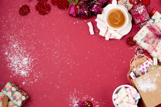 Eine Tasse duftenden Kaffee und Weihnachtsdekoration auf einem roten Hintergrund. Geschenke und Syootrizy für Weihnachten. Ansicht von oben. Rahmen. Kopieren Sie Platz