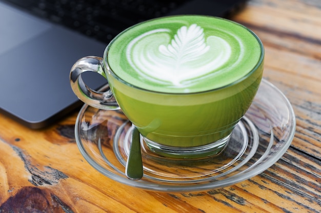 Eine Tasse grüner Tee der heißen Milch auf Tabelle