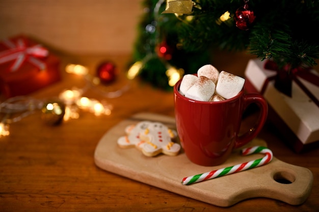 Eine Tasse heiße Schokolade mit Marshmallow-Lebkuchen und Süßigkeiten auf Holzbrett auf Holztisch