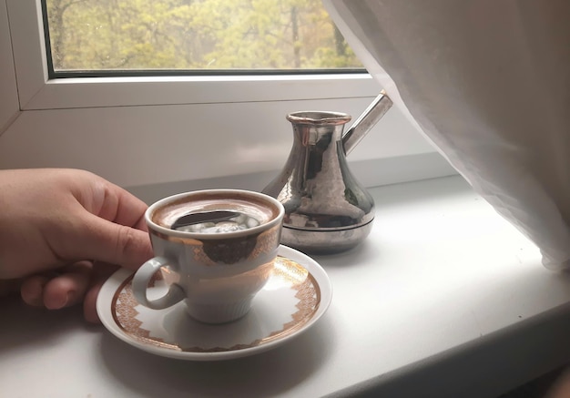 Eine Tasse heißen Espresso und ein Cezve am Morgen auf der Fensterbank Sanfte Farben Arabica-Aromakulisse