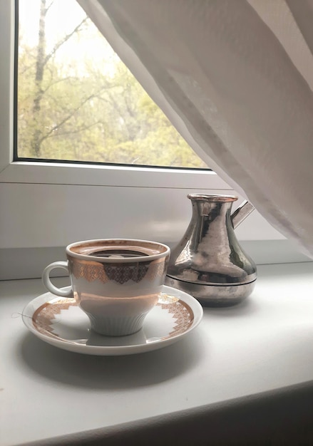 Eine Tasse heißen Espresso und ein Cezve am Morgen auf der Fensterbank Sanfte Farben Arabica-Aromakulisse