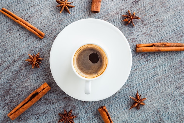 Eine Tasse Kaffee auf einem Teller und Zimt und Anissprossen verbreiteten sich um einen Stock