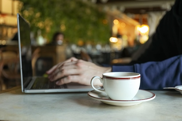 Eine Tasse Kaffee auf einem Tisch neben einem Laptop in einem Café