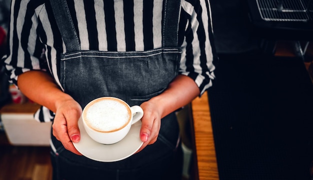 Eine Tasse Kaffee-Cappuccino-Menü bereit, in der Hand Frau Barista im Café zu servieren