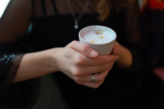 Eine Tasse Kaffee, die in den Händen des Mädchens 39 gehalten wird Hochwertiges Foto