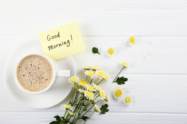 Foto eine tasse kaffee, ein blumenstrauß und eine karte mit den worten guten morgen