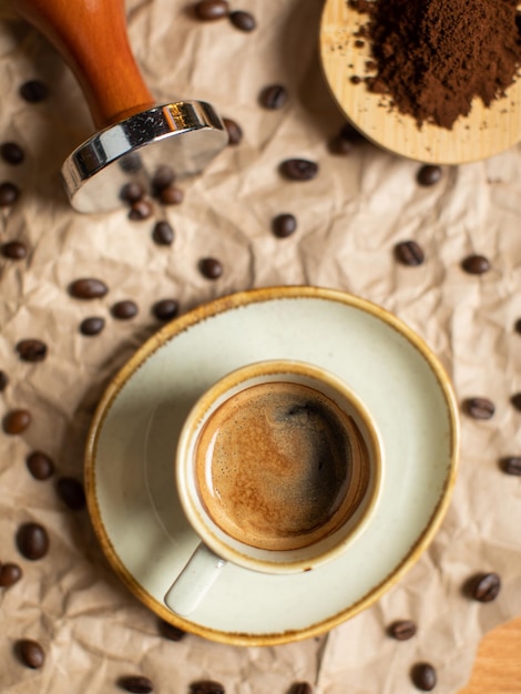 Eine Tasse Kaffee mit einem Löffel daneben und Kaffeebohnen auf einem Tisch.