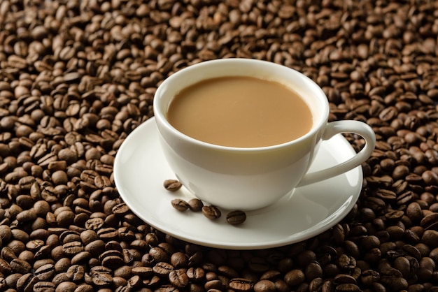 Eine Tasse Kaffee mit Milch Nahaufnahme auf dem Hintergrund von Kaffeebohnen