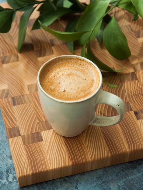 Eine Tasse Kaffee mit schönen Cremes auf einem Holzbrett