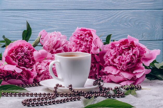 Eine Tasse Kaffee mit üppigen rosa Pfingstrosen